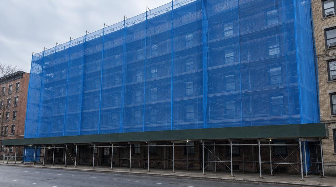 Illustration of a six-story frame scaffold wrapped in blue fire-retardant debris netting above a sidewalk shed